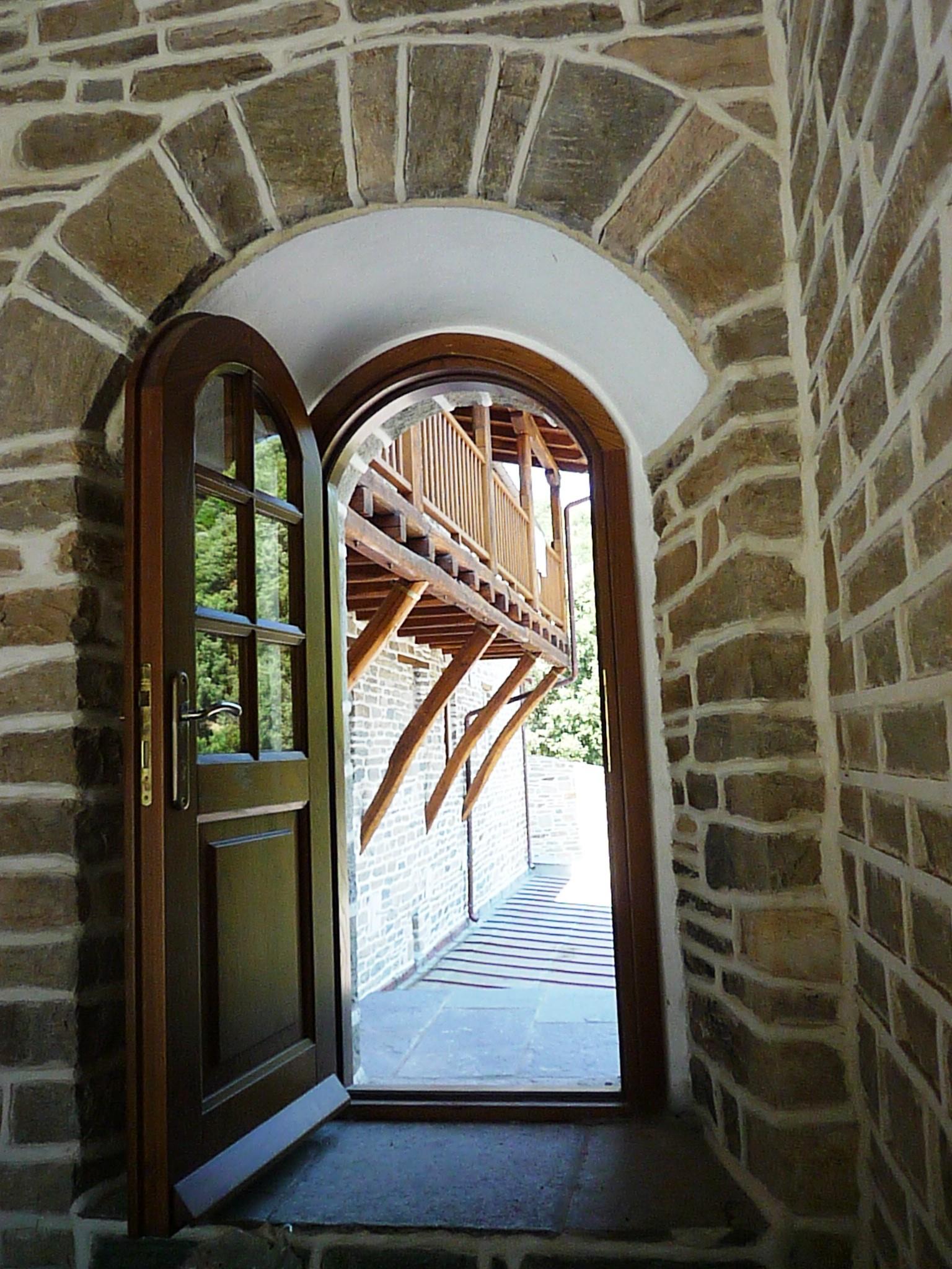 Ανοικτή ξύλινη τοξωτή πόρτα με τζάμια και καϊτια