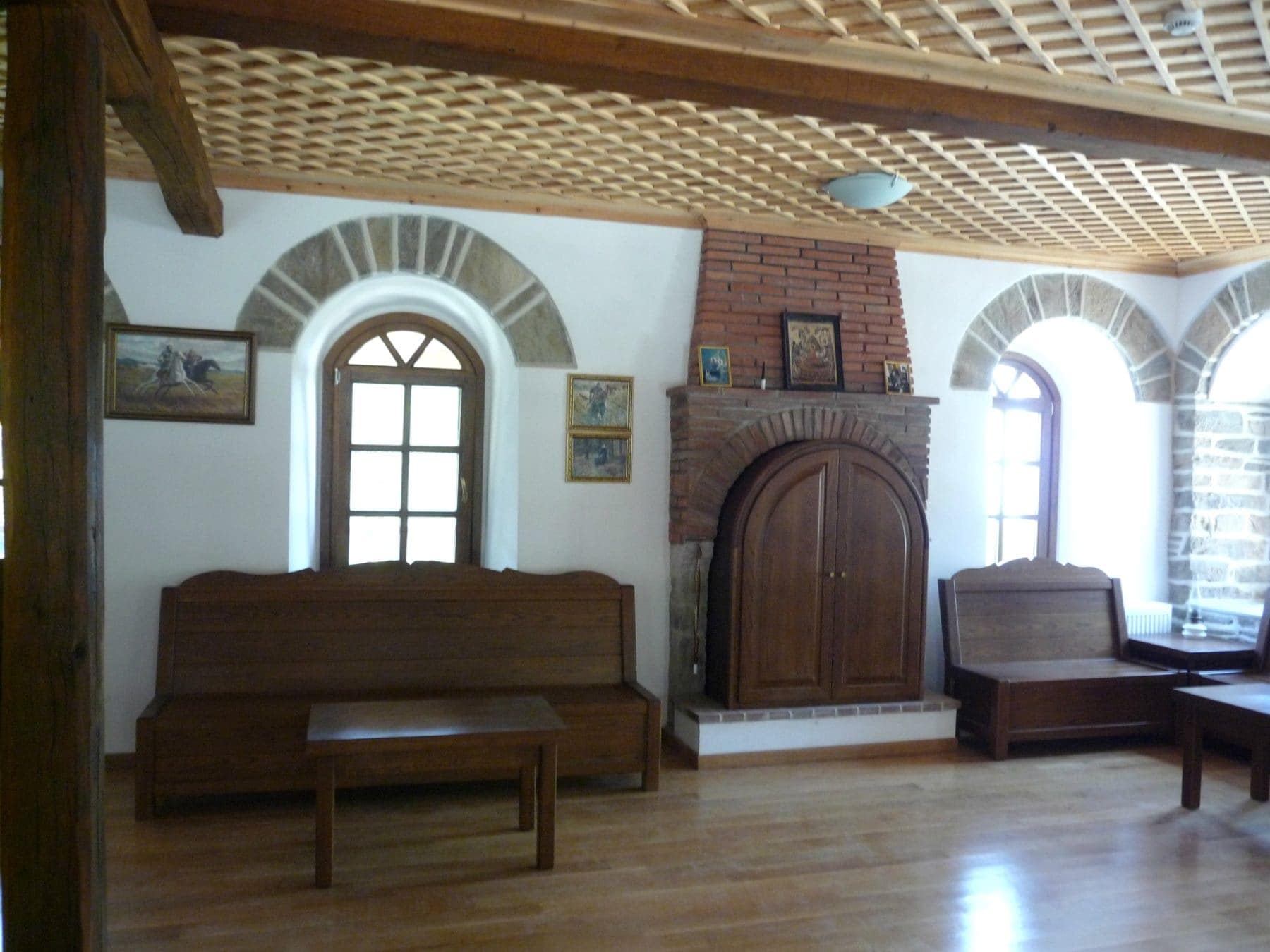 διακοσμημένο δωμάτιο με ξύλινα παράθυρα καναπέδες τραπεζάκια και προστατευτικό τζακιού